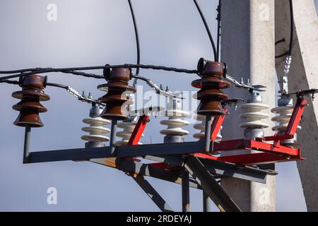 Overhead power line details. High voltage insulators and wires mounted on concrete pylon Stock Photo