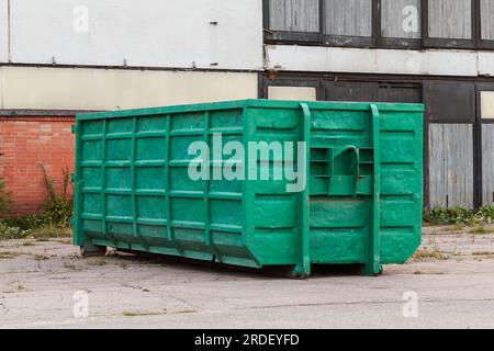 A large, metal, green garbage container and municipal waste, standing on a  dirt road near the fence and trees Stock Photo - Alamy