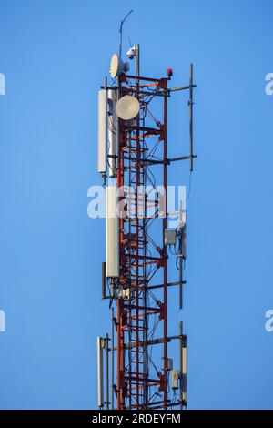 Telecommunication tower with radio devices is under blue sky on a daytime, vertical photo Stock Photo