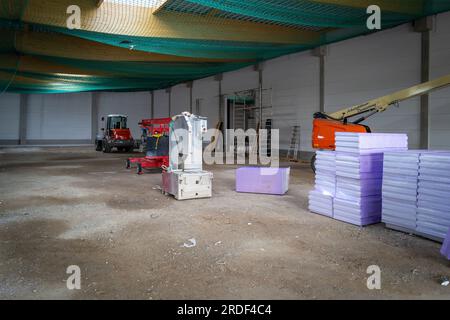 in the newly built factory hall there are styrofoam plates for insulation and various construction machines Stock Photo