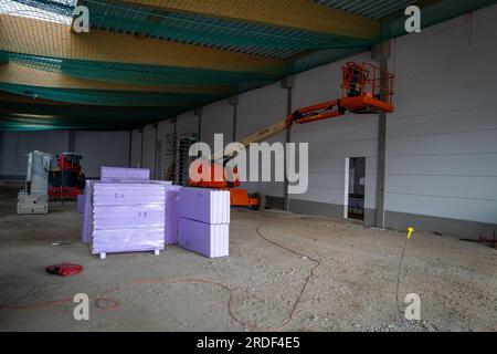 in the newly built factory hall there are styrofoam plates for insulation and various construction machines Stock Photo