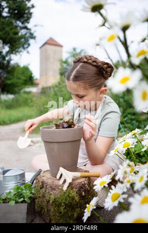 Girl planting green salad to grow in garden Stock Photo