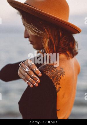 Young Woman in Brown Hat by Ocean With Silver Ring Splints Stock Photo