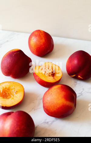 Ripe nectarines in the sun on a white tile with a tan background Stock Photo