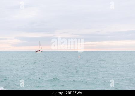 A sailboat on Lake Michigan against a pink streaked morning sky Stock Photo