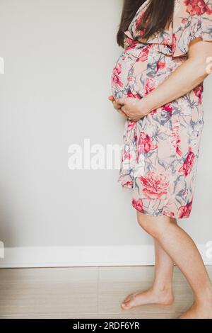 Pregnant Woman with Hands on Belly in Floral Dress Stock Photo