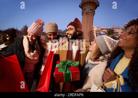 Smiling group diverse happy friends holding black Friday winter christmas shopping bags gifts. Stock Photo