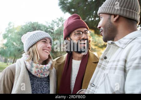 Three smiling friends enjoying sunny winter outdoors. Diverse joyful young people have fun together. Stock Photo