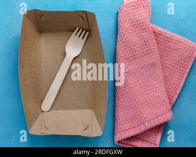 Empty paper plate and wooden fork on a blue background. Eco friendly materials. Diet for weight loss, weight loss. Food restrictions. Disposable paper Stock Photo
