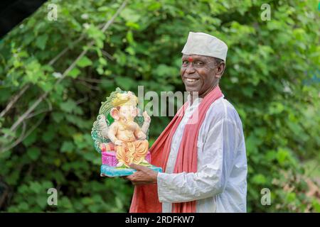 Indian old man holding Lord Ganesha idol in hands , happy old poor man Stock Photo