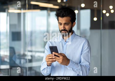 Indian young businessman sitting in an office center and using the phone. Stock Photo
