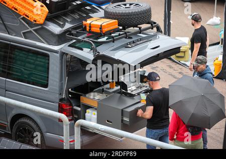 21 July 2023, Saxony-Anhalt, Gräfenhainichen: Visitors chat at the festival 'Vanlife-Ferropolis' at the rear kitchen on a VW camping bus. Until Sunday (21.07.) workshops and lectures are planned on the area. In addition, more than 40 exhibitors will present the latest innovations in caravanning, off-road, camping and vanlife at a trade fair. Photo: Jan Woitas/dpa Stock Photo