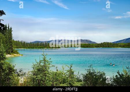 Transparent clear lake and two people in the water, tourism, Boya Provincial Park, Stewart Cessiar Highway, HW 37, British Columbia, Canada Stock Photo