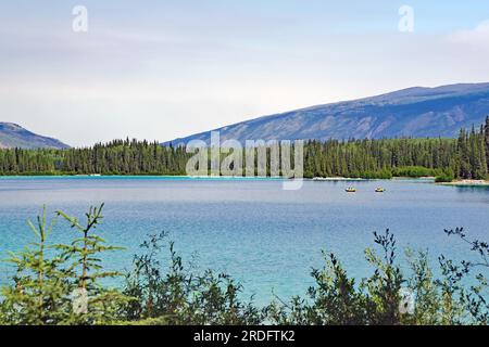 Transparent clear lake and small boats, Boya Provincial Park, Stewart Cessiar Highway, HW 37, British Columbia, Canada Stock Photo