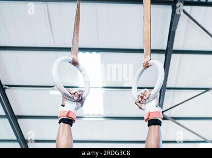 Hands, gymnastics ring and person in fitness for workout, strength training or competition. Closeup of hanging athlete, strong gymnast or acrobat Stock Photo