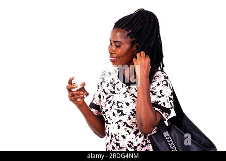 a beautiful mature woman with handbag standing over white background holding perfume smiling. Stock Photo
