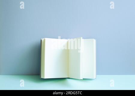 Open notebook on blue desk. blue wall background Stock Photo