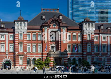 TOKYO, JAPAN - JULY 16 2023: Small crowds of people around the red brick building of Tokyo Central Station on a hot summers day Stock Photo