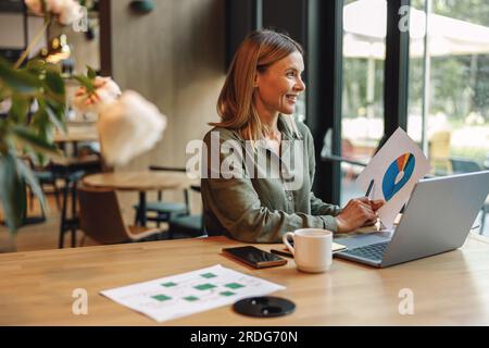 Woman analyst working with documents and use laptop sitting in modern coworking Stock Photo