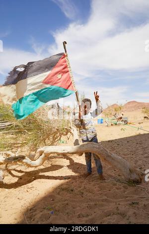 Bedouin boy holding up Jordanian flag, Wadi Rum, Aquaba, Jordan Stock Photo