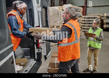 Workers working in team in warehouse, they loading boxes in truck Stock Photo