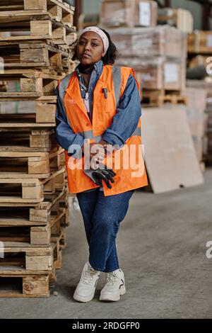 Vertical portrait of African American female worker in workwear working in warehouse Stock Photo