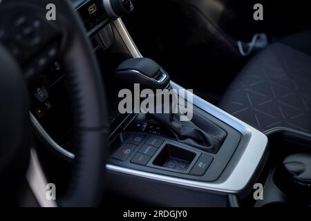 A portrait of an automatic gear shift stick in a hybrid car, meaning it drives on fossil fuel and electricity. The shifter has 4 positions, park, reve Stock Photo