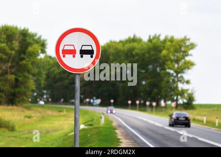 The overtaking sign is prohibited on the background of a highway with passing cars Stock Photo