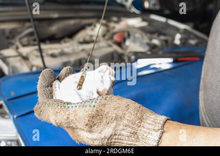 A man is engaged in car maintenance, checks the engine oil level after replacing it with a new one Stock Photo