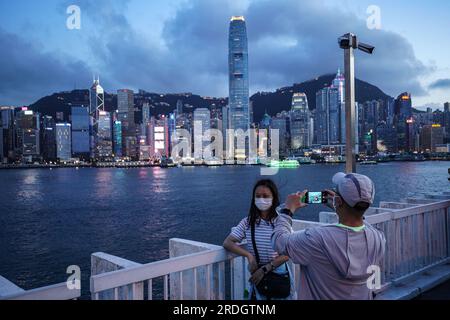 People take photos in front of Victoria Harbour at Tsim Sha Tsui. Stock Photo