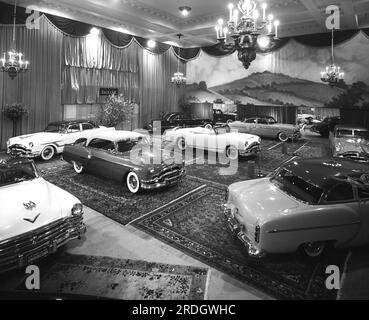 United States:  1953 A portion of an auto show with several Packards and one Chrysler New Yorker Deluxe convertible at the left. Stock Photo