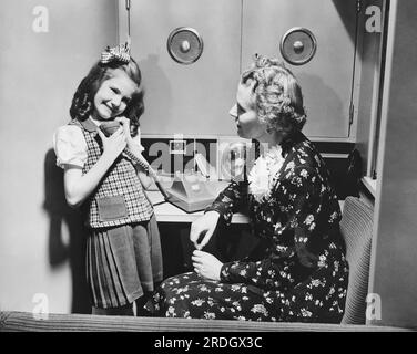 United States:  1947 Passengers on General Motor's new experimental train, the 'Train of Tomorrow' now have access to 'ship to shore' telephones. A young girl is shown talking on the phone while her mother waits. Stock Photo