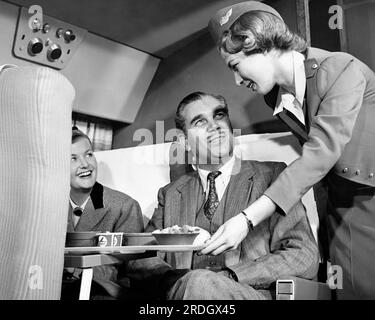 United States:  c. 1953 A Capital Airlines stewardess serves food and beverages to two passengers. Stock Photo