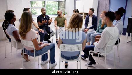 Young Multiracial Millennial Friends Sitting In Circle Having Group Discussion Stock Photo