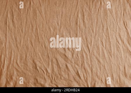Wrinkled, crumpled brown fabric texture background. Wrinkled and creased abstract backdrop of cotton jersey textile, wallpaper with copy space, top vi Stock Photo