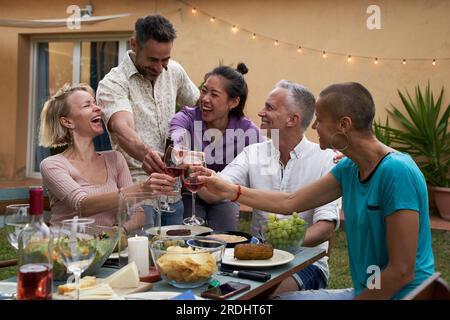 Middle-aged People clinking glasses with wine on the summer. Friends having fun together outside. Stock Photo