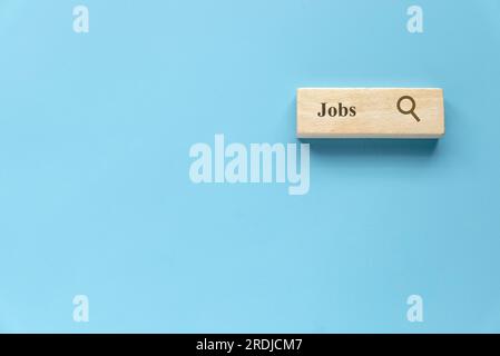 Searching for a new job, employment, a career, a job opportunity, or a work position concept. Wooden search bar isolated on a blue background with cop Stock Photo
