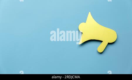 Concept of announcement, vacancy information, join us. Yellow megaphone paper on blue background with copy space. Stock Photo