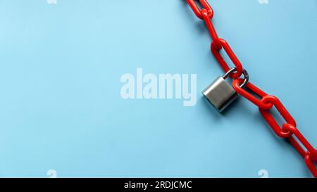 Safety concept. Red chain and padlock on blue background. Copy space. Stock Photo