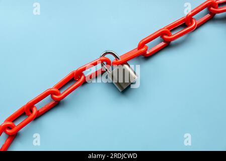 Safety concept. Red chain and padlock on blue background. Stock Photo