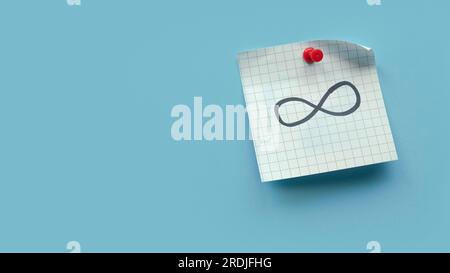 Infinity sign or symbol handwritten on a memo note over blue background. Stock Photo