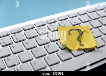 Q&A or questions and answers concept. Yellow sticker with handwritten question symbol over computer keyboard. Stock Photo
