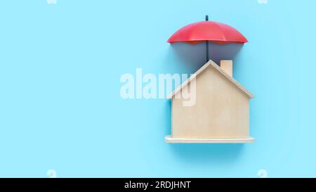 Concept of property insurance, mortgage, real estate. Umbrella over a wooden house model. Stock Photo