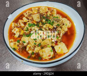 Numb and spicy tofu in the red oil in the plate for eating Stock Photo