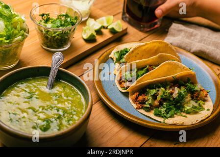 Marinated beef tacos, bowl with salsa verde and vegetables on a wooden table. Tacos de adobada. Stock Photo