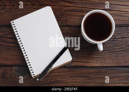Cup of coffee and opened notebook with pen on wooden background. Top view Stock Photo