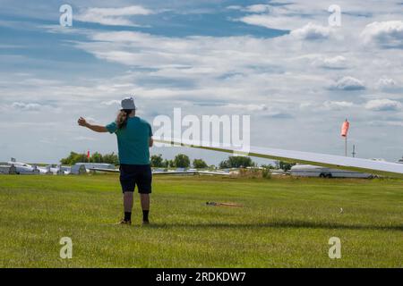 A man holds the wing of a glider while it waits to be towed along the runway in England in the UK Stock Photo