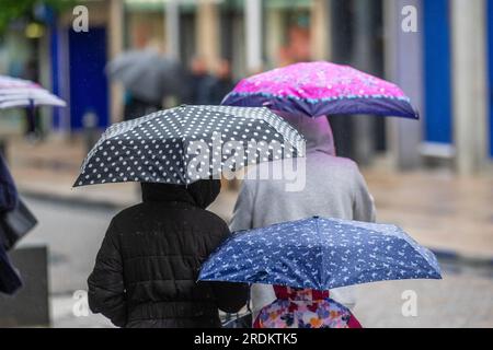 Shoppers all holding umbrellas on a rainy in Preston Lancashire.  UK Weather 22 July 2023. Summer sales, shops, and shoppers on a rainy day in the city centre. Forecasters say: 'Rain, heavy at times, through Saturday & Sunday is likely to cause some disruption, particularly to outdoor events. Stock Photo