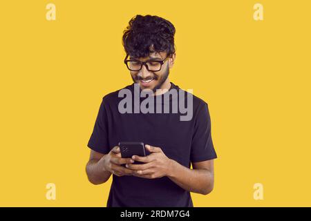 Young Indian man chatting with phone and reading SMS with smile using instant messengers app Stock Photo