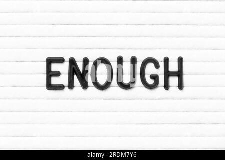 Black color letter in word enough on white felt board background Stock Photo